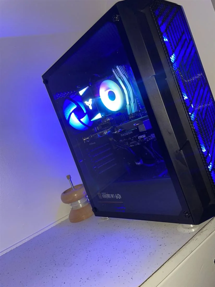 A real D Builds machine: a black Kratos M1 60 full tower lit deep blue, photographed on delivery day.